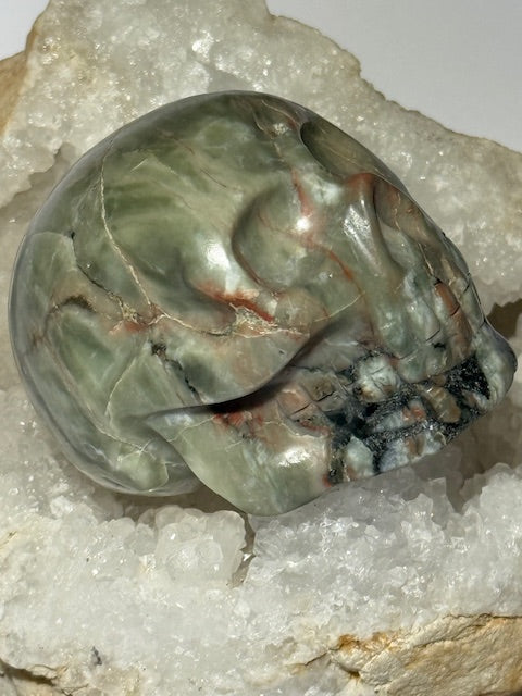 Crâne en émeraude verte avec inclusions de bixbite (émeraude rouge)