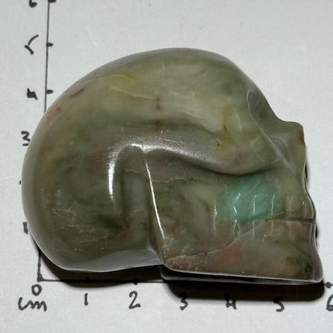 Crâne en émeraude verte avec inclusions de bixbite (émeraude rouge)